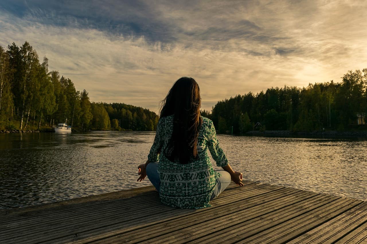 Auf dem Bild ist eine Person zu erkennen, die eine Meditation gegen Stress macht.